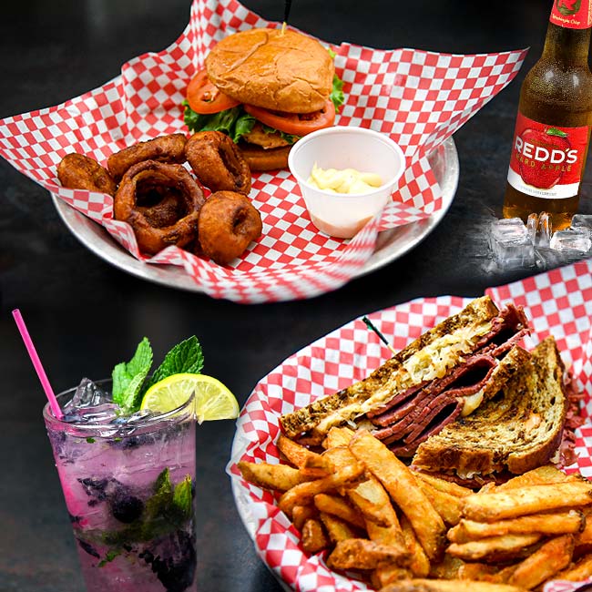 Rebuen sandwich and fries along side a chicken sandwich topped with lettuce and tomato, served with fruit cocktail drink and bottled Reds Apple Ale at VFW 1215 and The mess Hall in Rochester, MN.